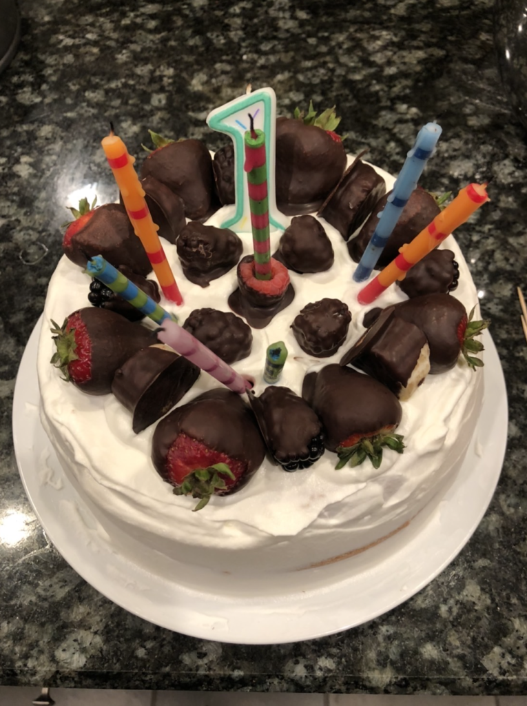 A chiffon cake decorated with chocolate covered berries and colorful candles representing the number sixteen.