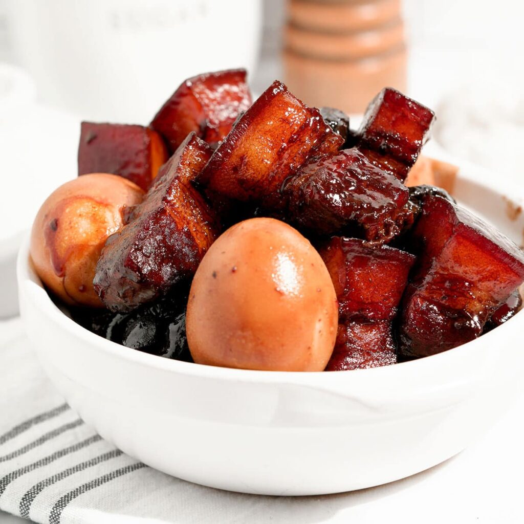 One white bowl with briased pork belly and tea eggs, small pieces piling on top of each other